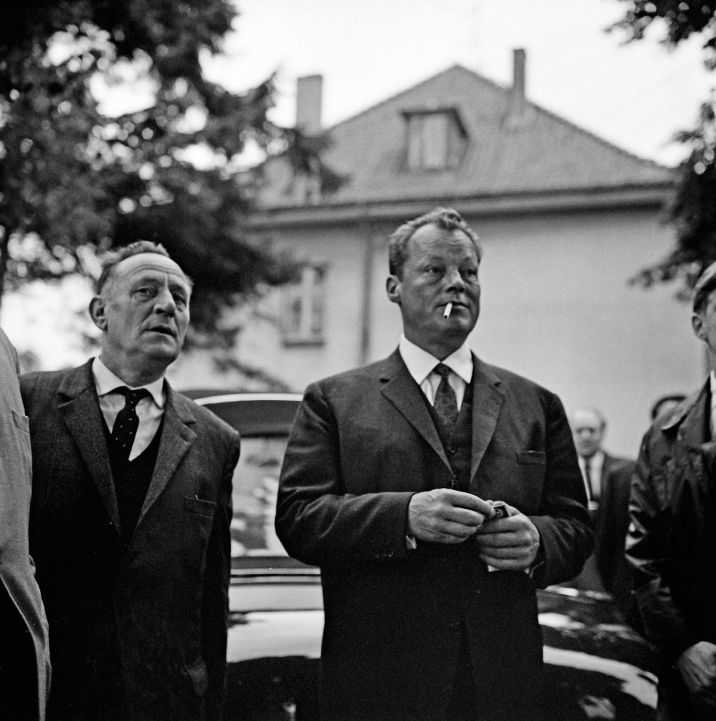 Bad Oldesloe: SPD: Bürgerpark: Naturtheater: Kundgebung zur Bundestagswahl am 19. September 1965: Ankunft des Kanzlerkandidaten Willy Brandt, SPD-Parteivorsitzender und Regierender Bürgermeister von Berlin, mit dem Landtagsabgeordneten Otto Gramcko: dahinter Pkw: hinten Gebäude und Ehrengäste: 18. September 1965